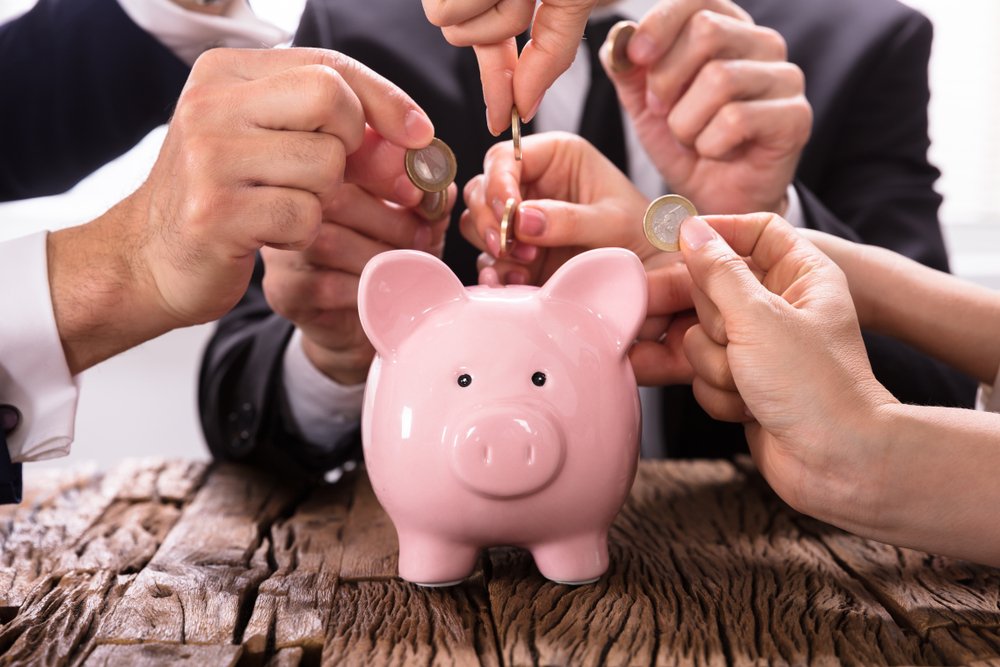 People in suits putting coins into piggy bank