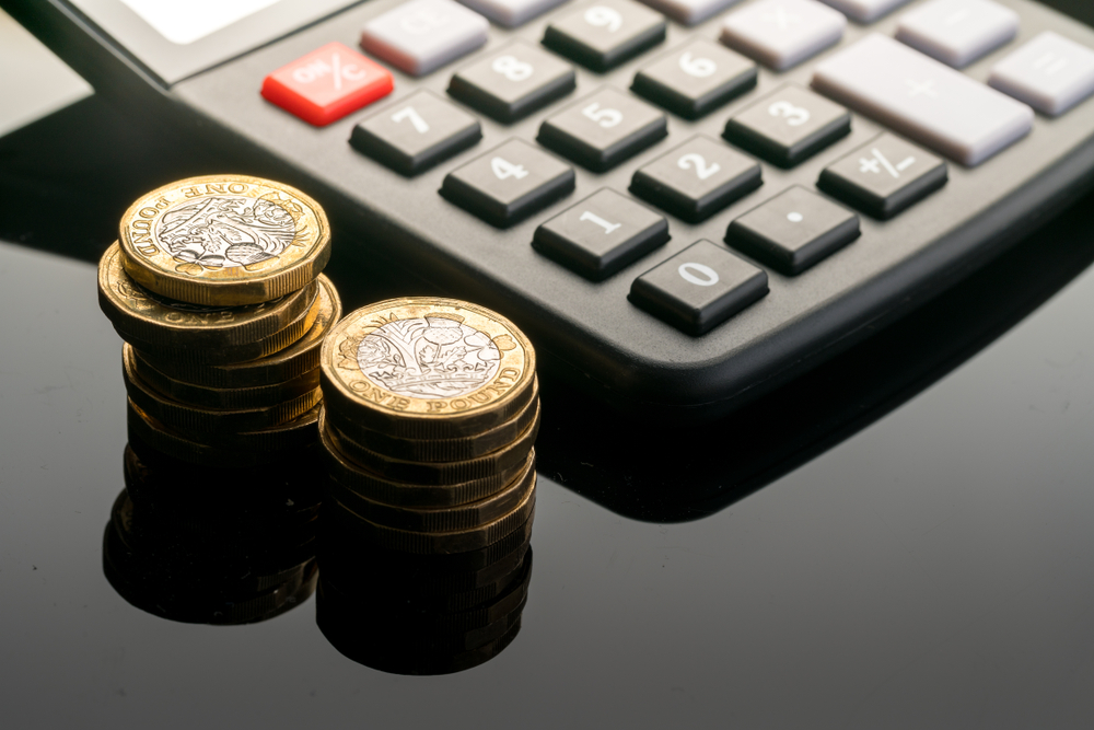 Calculator on a table next to some pound coins