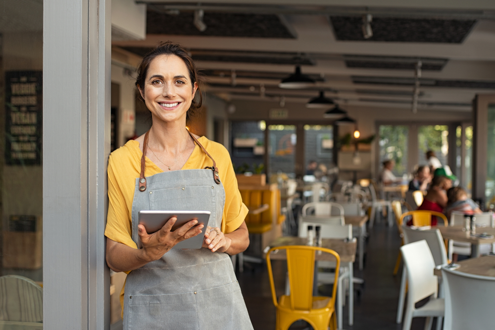 Smiling owner at door of her restaurant business
